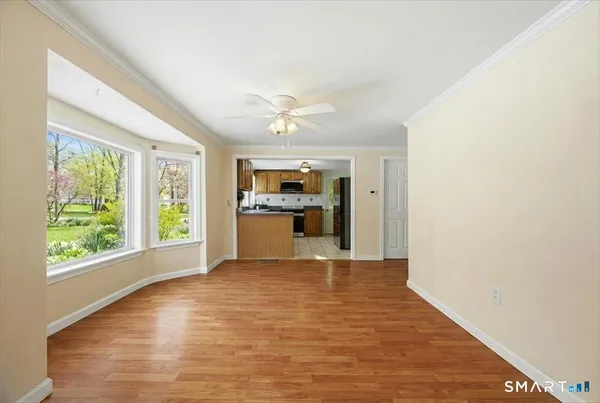 a view of an empty room with a window and kitchen view