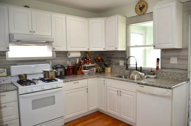 a kitchen with granite countertop white cabinets white appliances and a sink