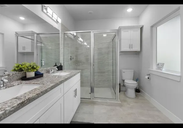 a bathroom with a granite countertop sink a toilet and shower