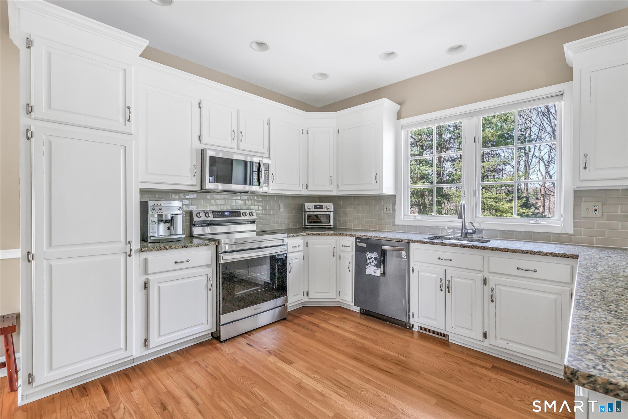 111 Stones Throw Trumbull, CT 06611 - Photo 15 of 47 a kitchen with stainless steel appliances granite countertop a stove a sink and white cabinets with wooden floors