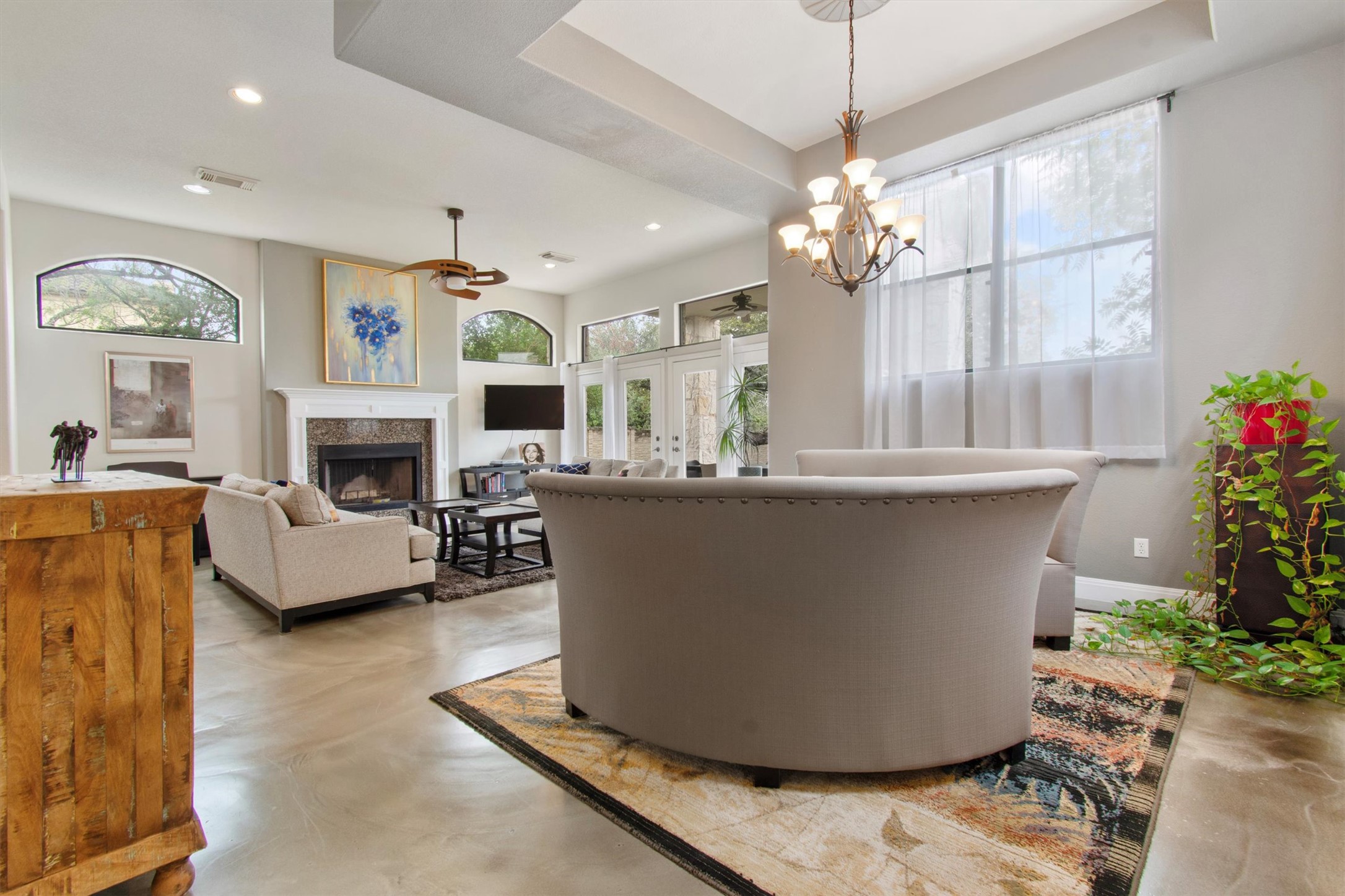 6 Monarch Oaks Lane Austin, TX 78738 - Photo 13 of 40 Living room featuring concrete floors, a fireplace, a ceiling fan, a tray ceiling, and recessed lighting