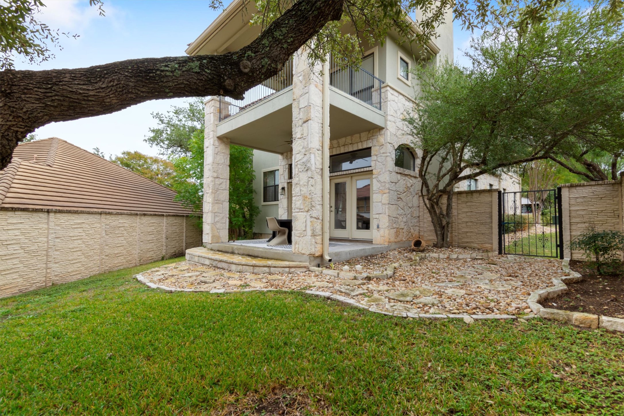 6 Monarch Oaks Lane Austin, TX 78738 - Photo 33 of 40 Back of house with a balcony, a patio area, a gate, french doors, and stone siding