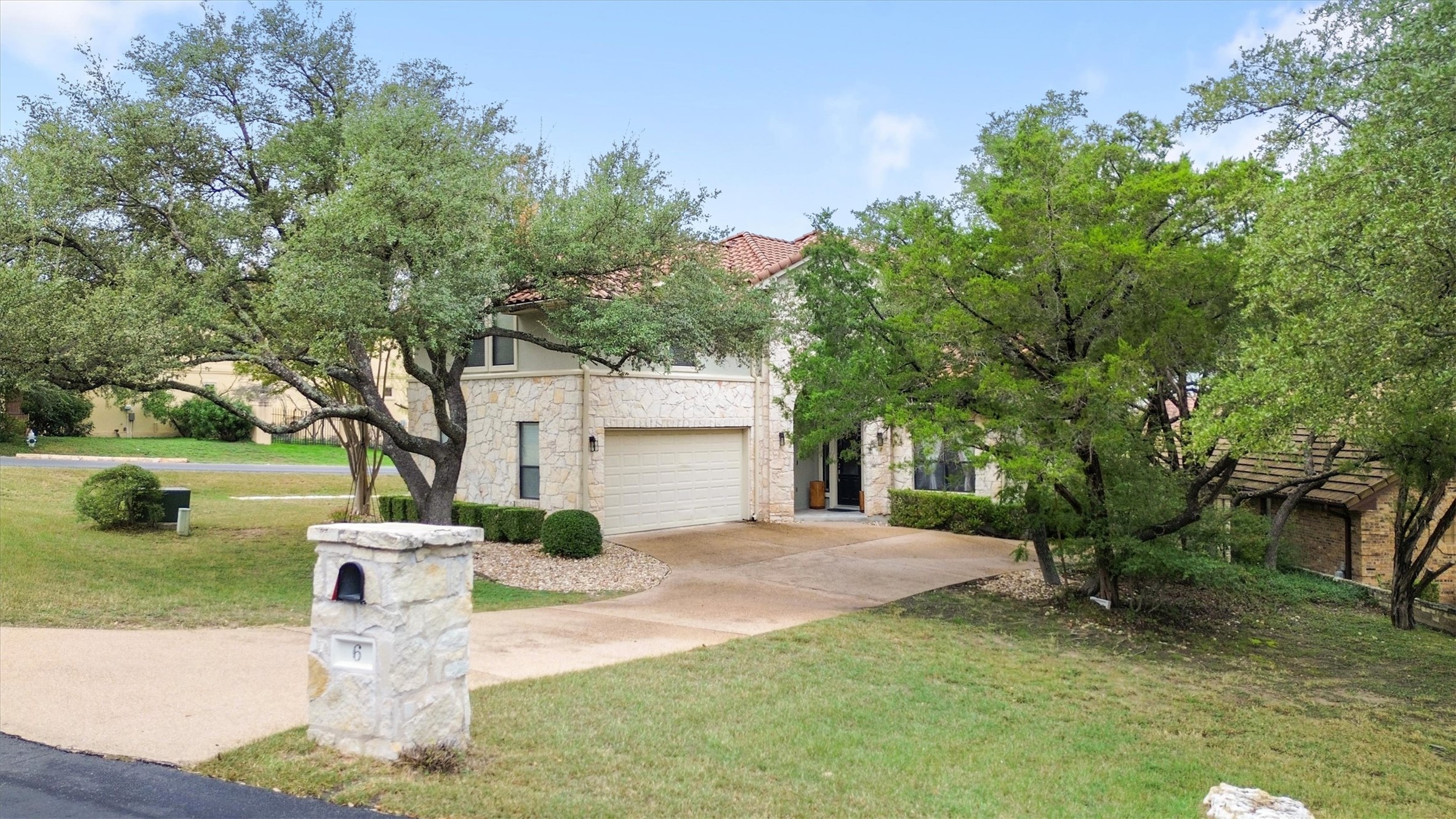 6 Monarch Oaks Lane Austin, TX 78738 - Photo 37 of 40 View of front facade with a front yard, concrete driveway, stone siding, a garage, and a tile roof
