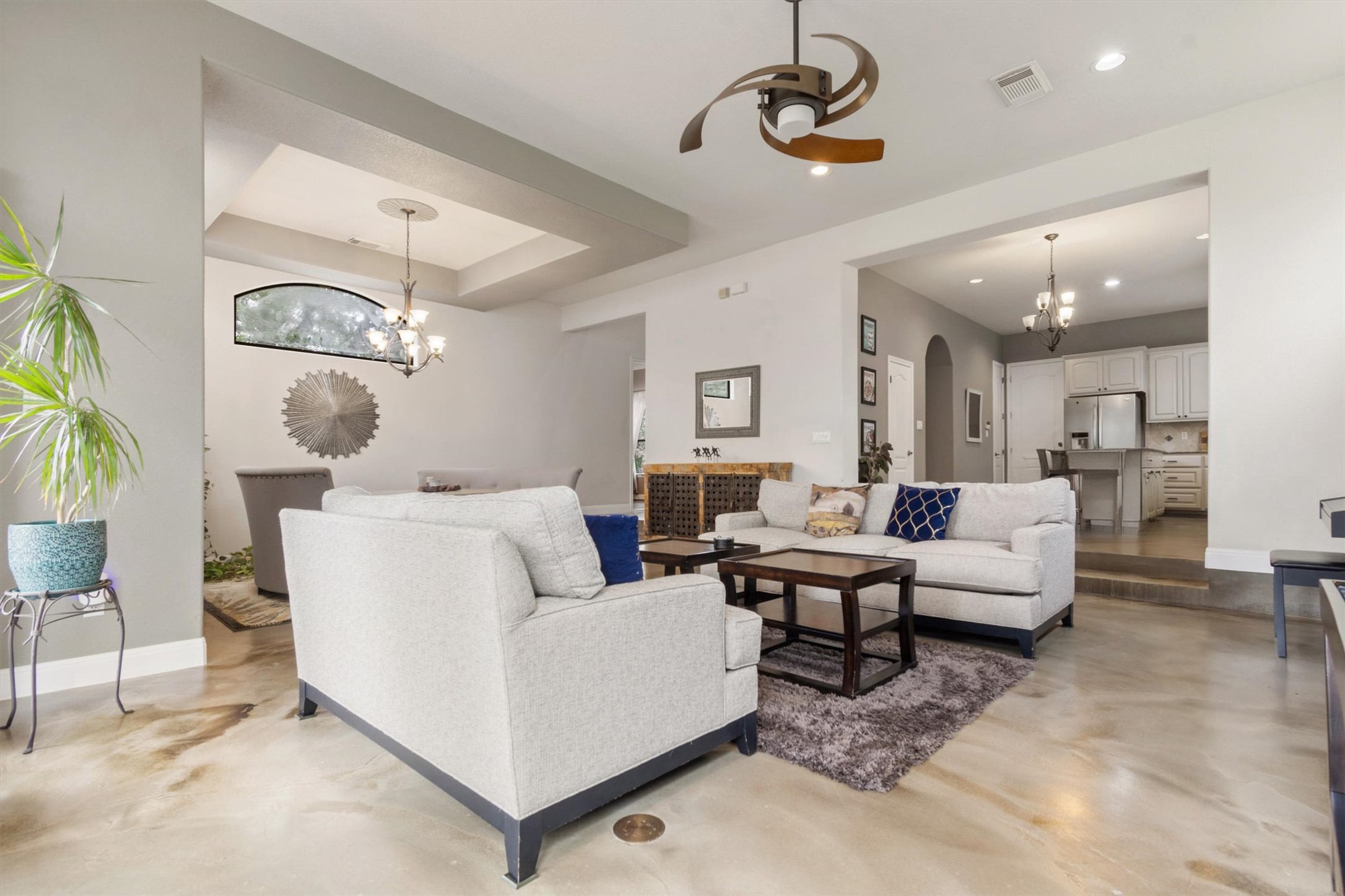 6 Monarch Oaks Lane Austin, TX 78738 - Photo 6 of 40 Living room featuring a chandelier, a raised ceiling, finished concrete floors, ceiling fan, and arched walkways