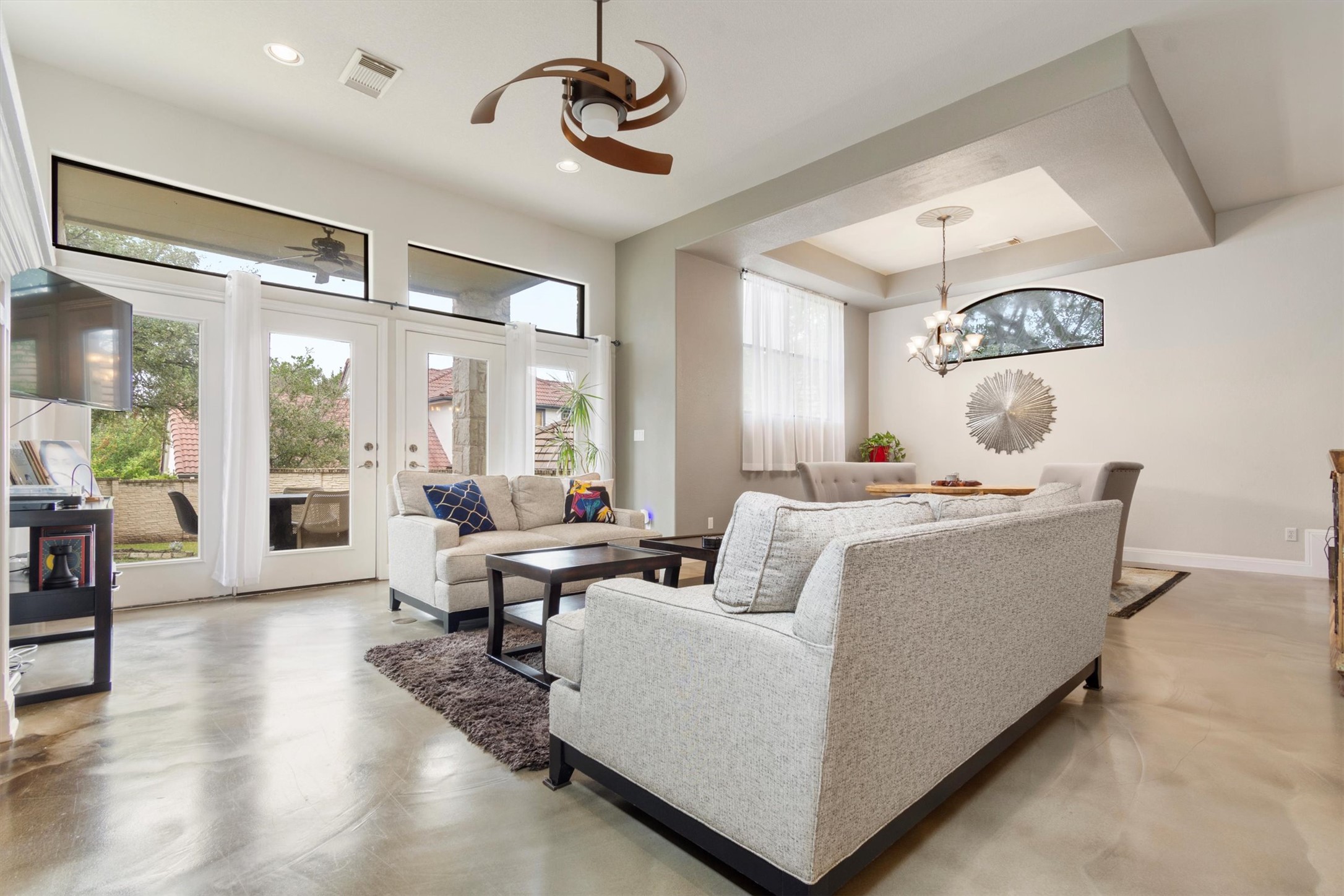 6 Monarch Oaks Lane Austin, TX 78738 - Photo 7 of 40 Living area with concrete floors, a raised ceiling, a chandelier, and french doors
