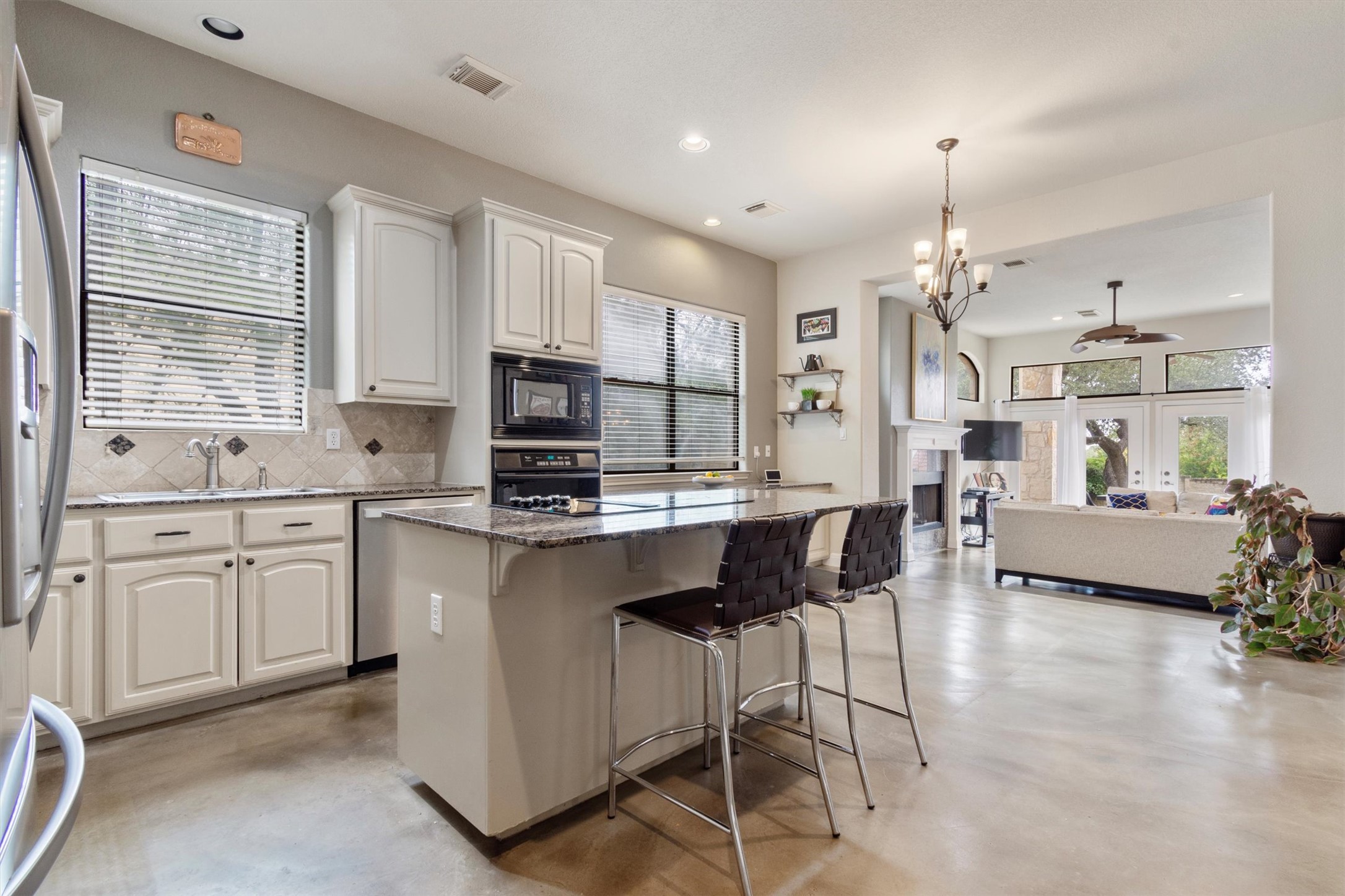 6 Monarch Oaks Lane Austin, TX 78738 - Photo 8 of 40 Kitchen with dark stone counters, a kitchen bar, concrete flooring, pendant lighting, and a center island