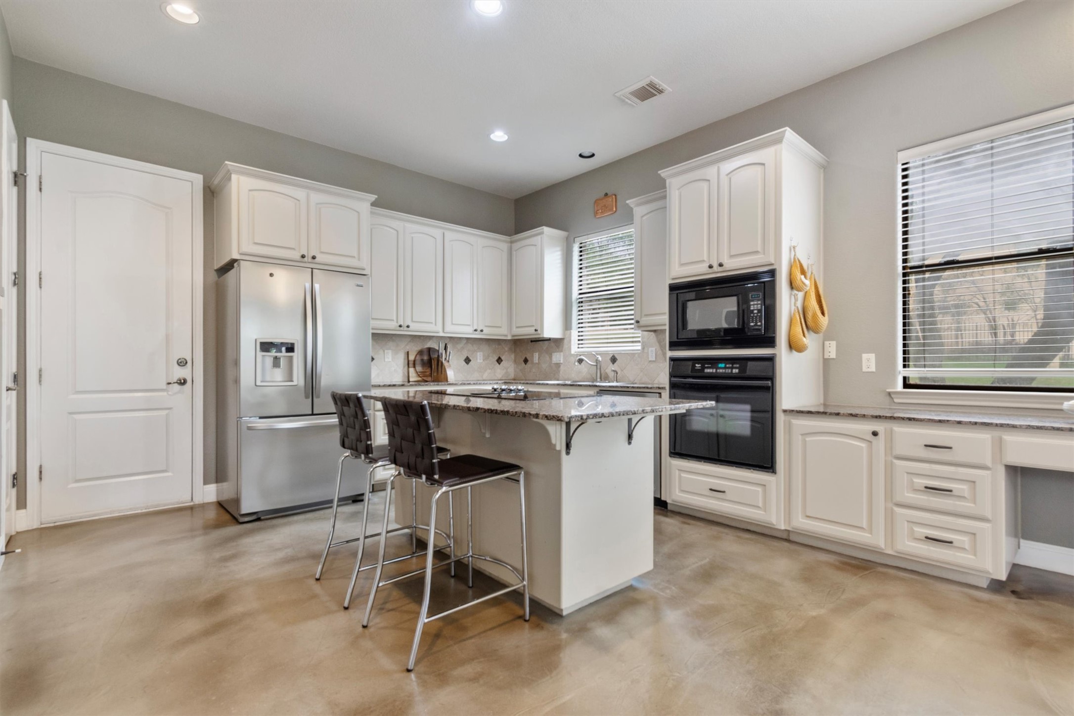 6 Monarch Oaks Lane Austin, TX 78738 - Photo 9 of 40 Kitchen with black appliances, light stone counters, a breakfast bar area, white cabinetry, and recessed lighting