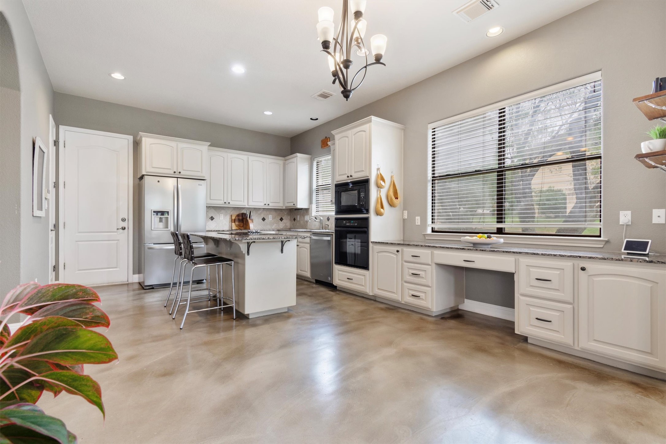 6 Monarch Oaks Lane Austin, TX 78738 - Photo 10 of 40 Kitchen featuring a kitchen bar, white cabinetry, black appliances, pendant lighting, and light stone countertops