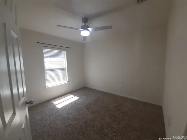an empty room with a fan & a ceiling fan