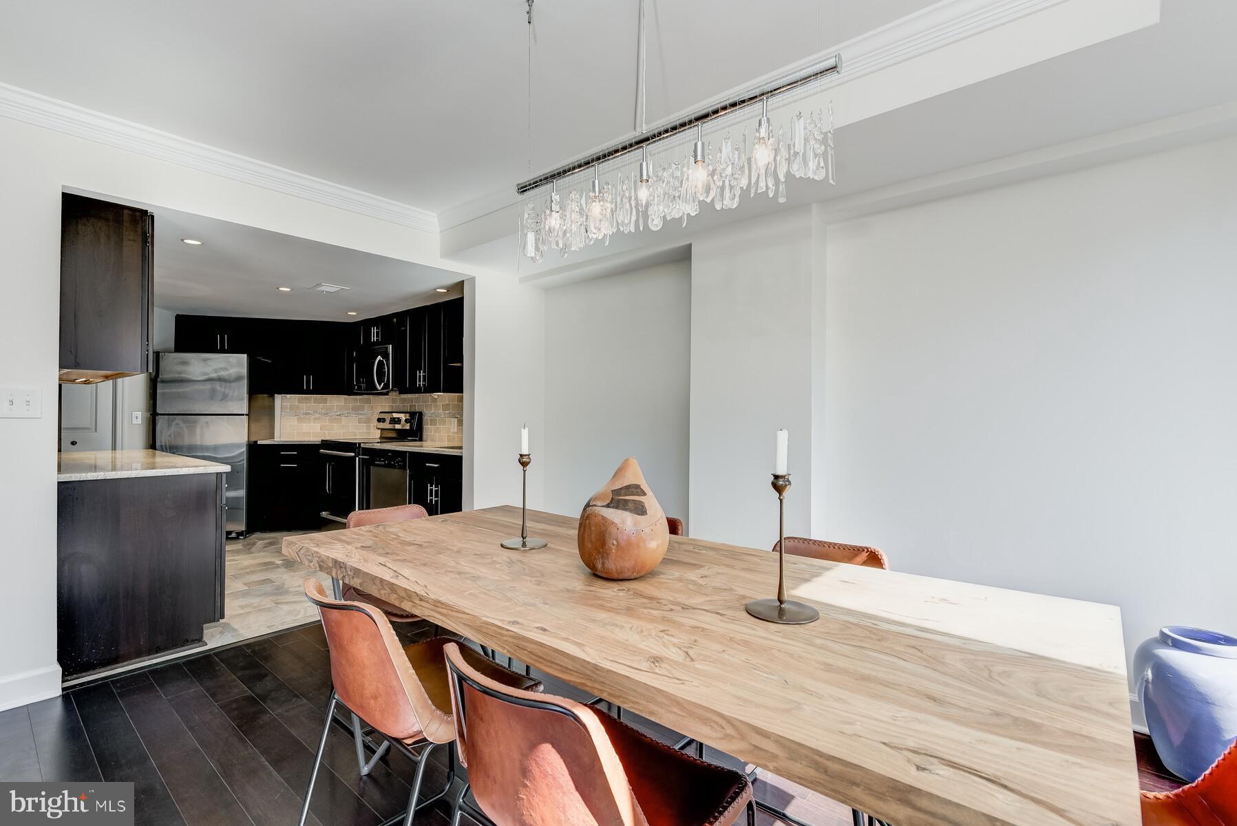 1080 Wisconsin Avenue Northwest, Unit 2001 Washington, DC 20007 - Photo 12 of 30 a kitchen with stainless steel appliances wooden floor dining table and chairs