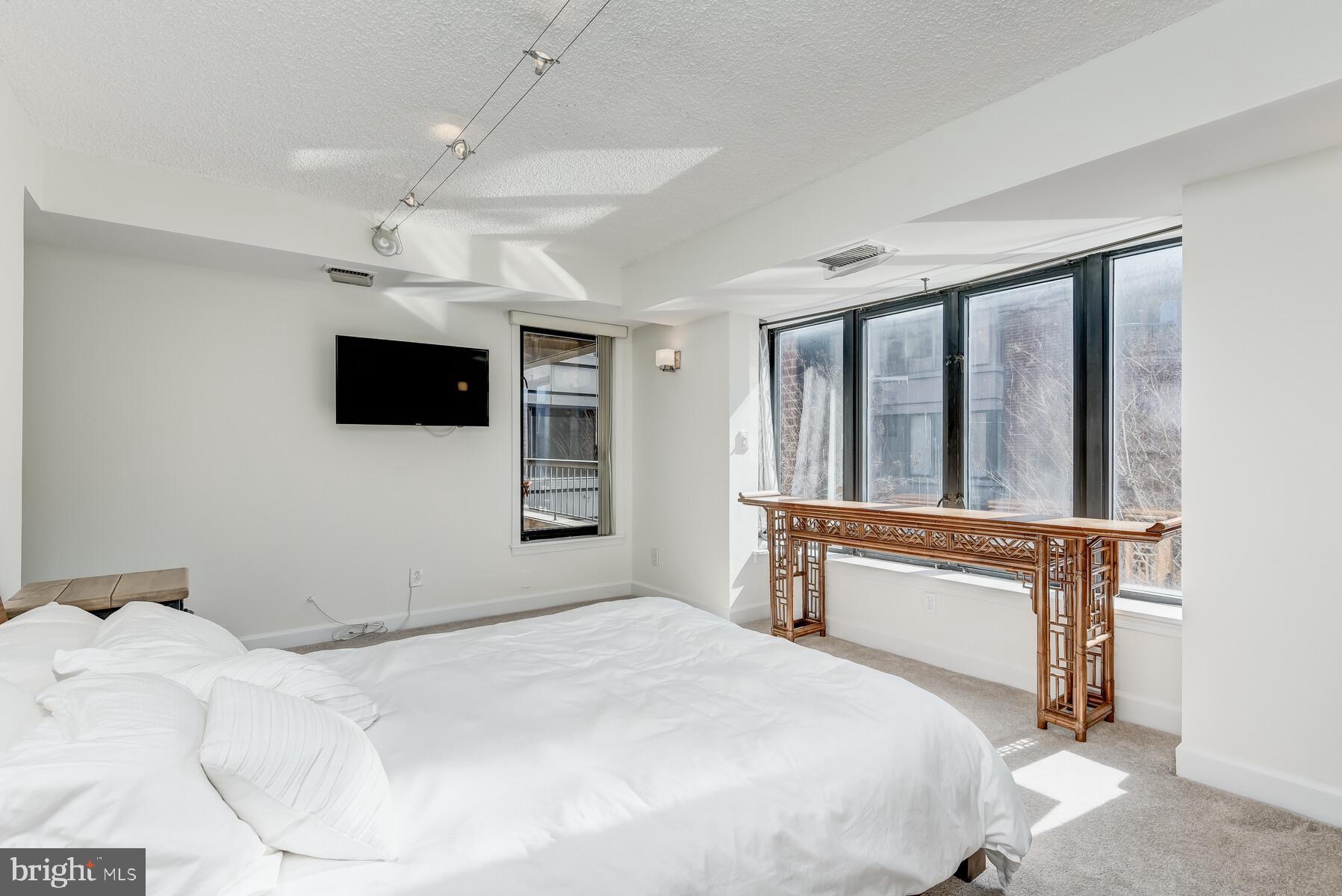 1080 Wisconsin Avenue Northwest, Unit 2001 Washington, DC 20007 - Photo 19 of 30 a bedroom with a large bed and a flat tv screen