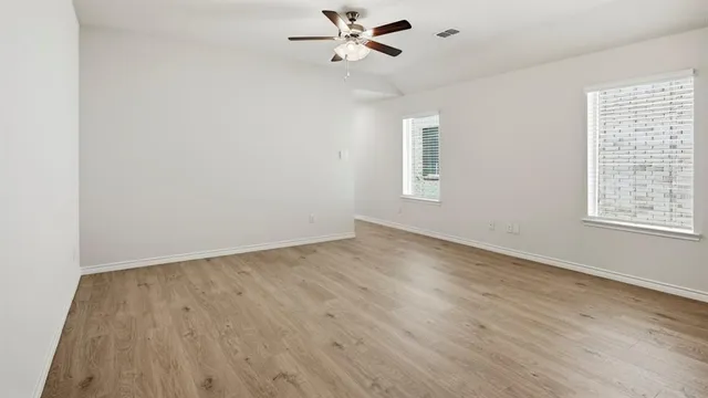 an empty room with wooden floor and fan