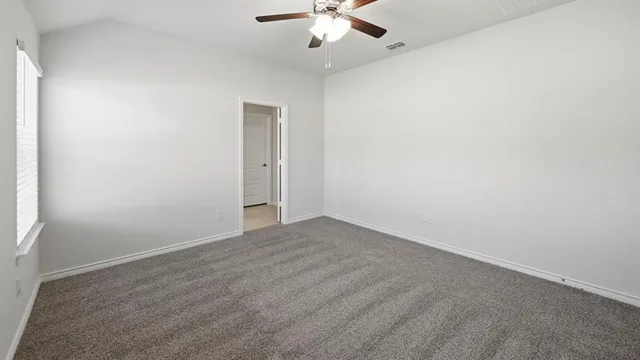 an empty room with a ceiling fan and a window