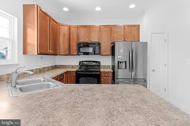 a kitchen with kitchen island a counter top space appliances and a sink