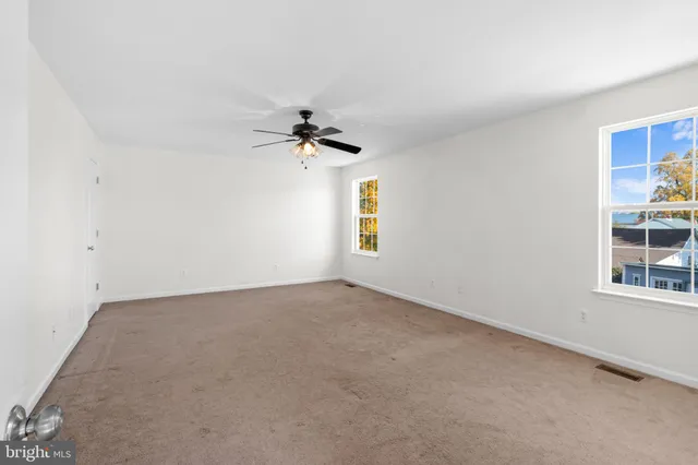 an empty room with windows and ceiling fan view