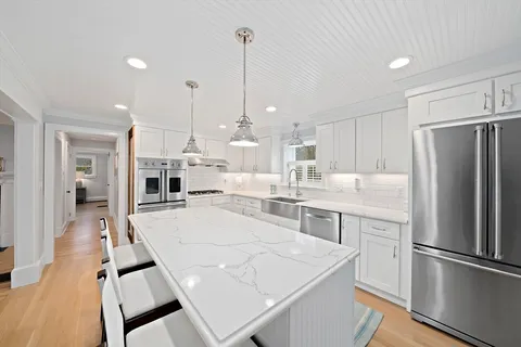 a large kitchen with kitchen island a stove a sink a refrigerator and a view of living room