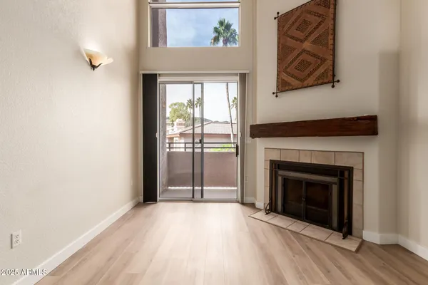 a view of an empty room with wooden floor and a fireplace