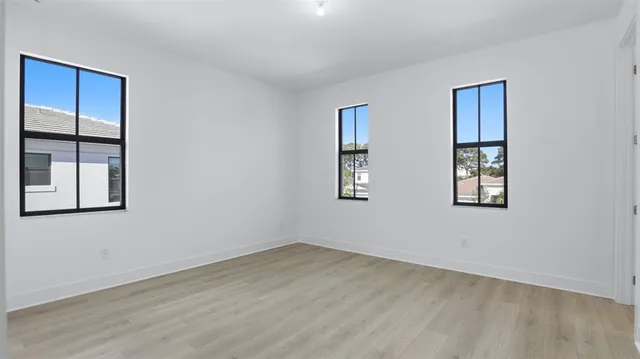 a view of an empty room with a window and wooden floor