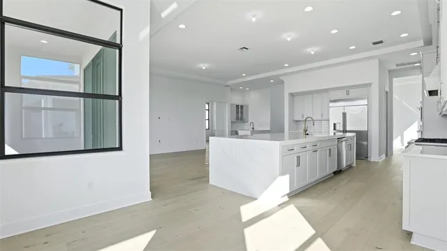 a large white kitchen with kitchen island a sink a center island stainless steel appliances and a cabinets