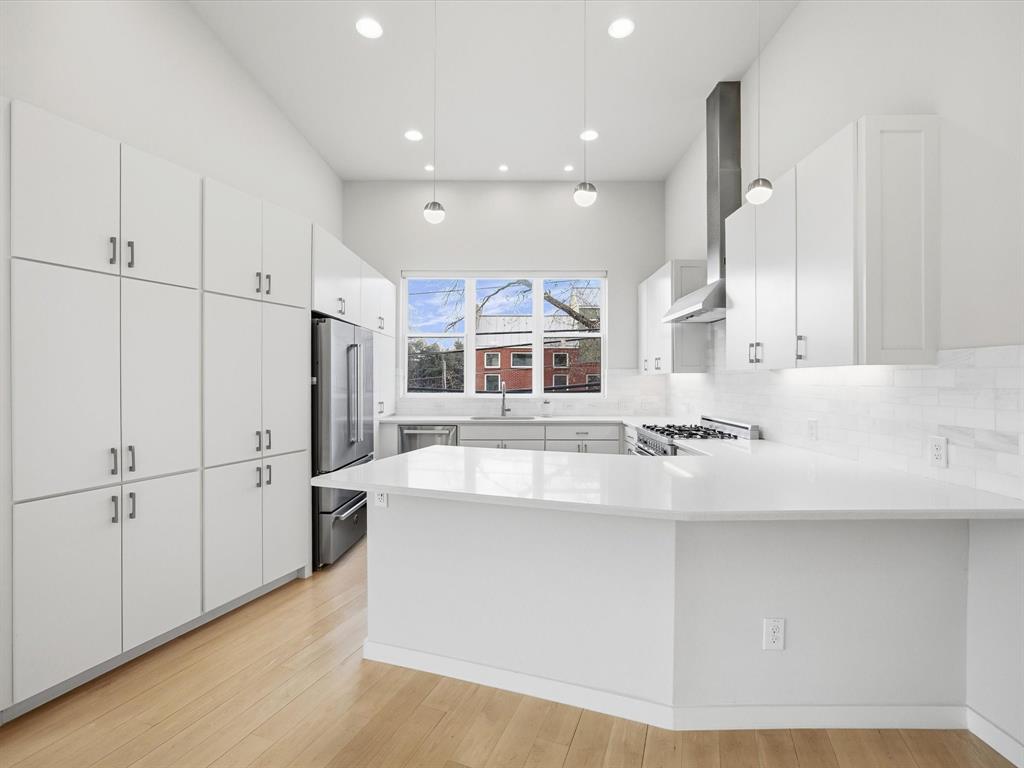 2802 Lee Street Dallas, TX 75206 - Photo 12 of 40 a large white kitchen with kitchen island a stove a sink and a refrigerator