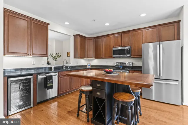 a kitchen with stainless steel appliances granite countertop a table chairs sink refrigerator and cabinets