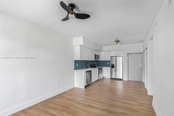 a kitchen with a refrigerator and white cabinets