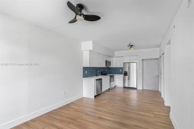 a kitchen with a refrigerator and white cabinets