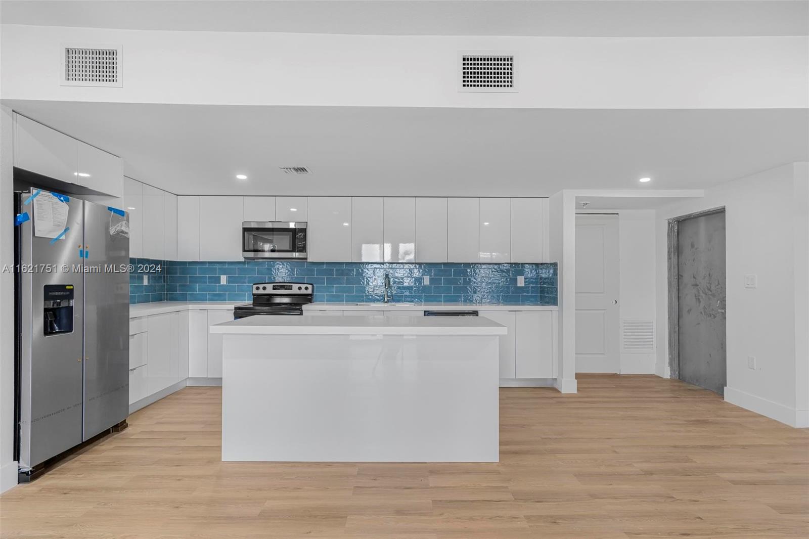16955 Southwest 100th Avenue Miami, FL 33157 - Photo 18 of 36 a large kitchen with stainless steel appliances granite countertop a stove a refrigerator a sink and white cabinets with wooden floor