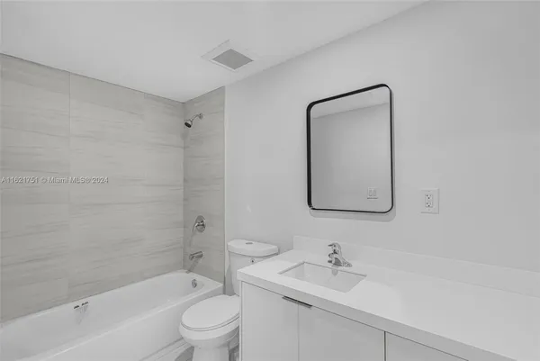 a bathroom with a bathtub shower sink mirror and toilet