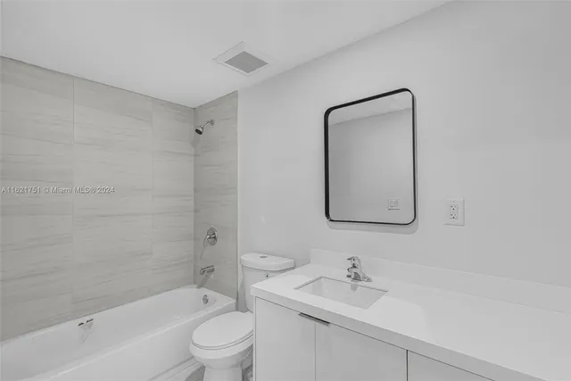 a bathroom with a bathtub shower sink mirror and toilet