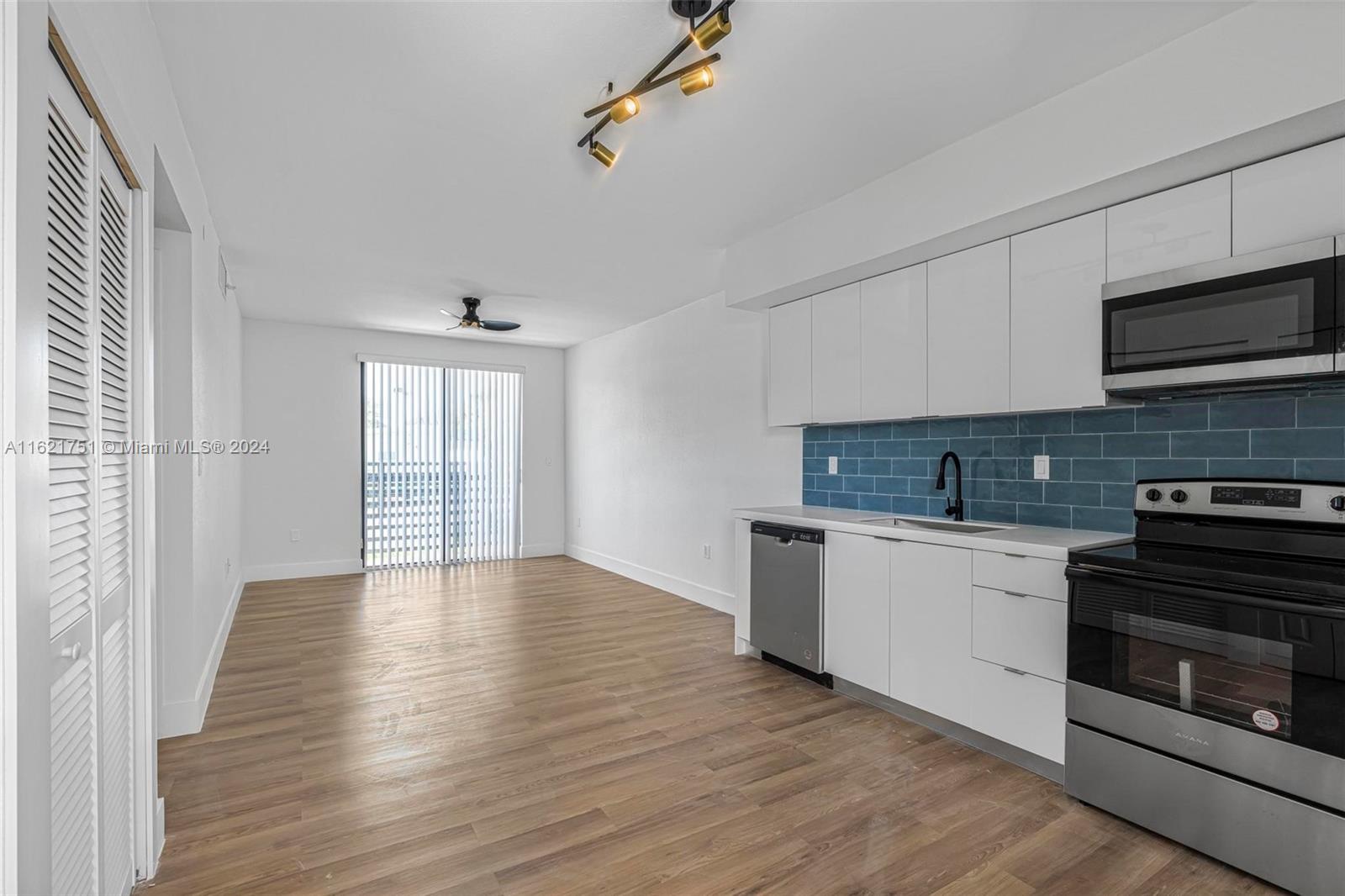 16955 Southwest 100th Avenue Miami, FL 33157 - Photo 6 of 36 a kitchen with granite countertop a stove top oven a sink and dishwasher a refrigerator with wooden floors