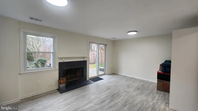an empty room with windows a fireplace and wooden floor
