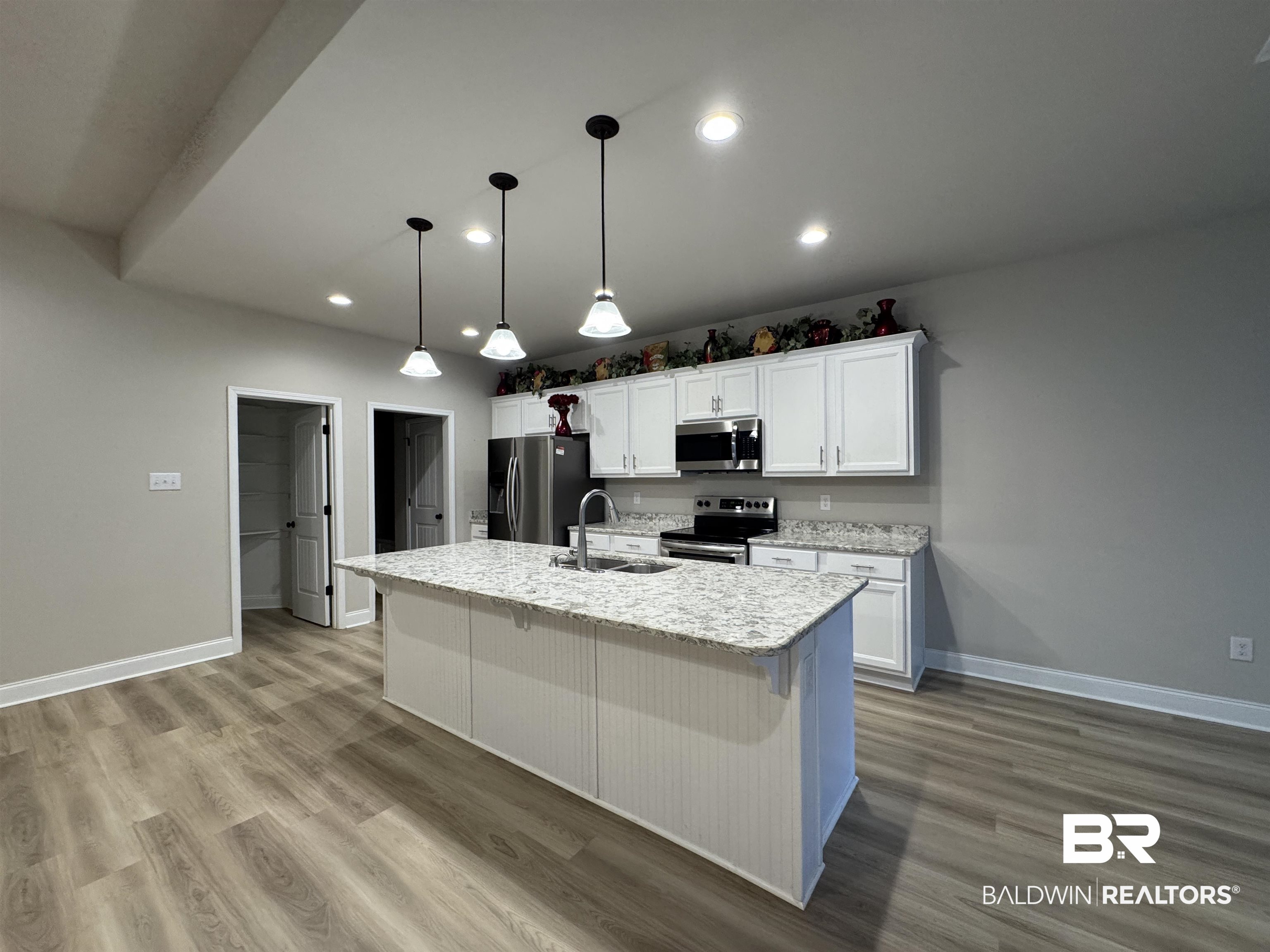 1060 Chloe Street Foley, AL 36535 - Photo 11 of 28 Kitchen featuring a central island with white beadboard paneling, granite countertops, and a stainless steel sink with a gooseneck faucet