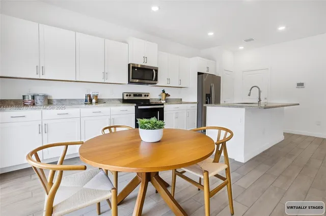 a kitchen with stainless steel appliances granite countertop a kitchen island a stove a table and chairs