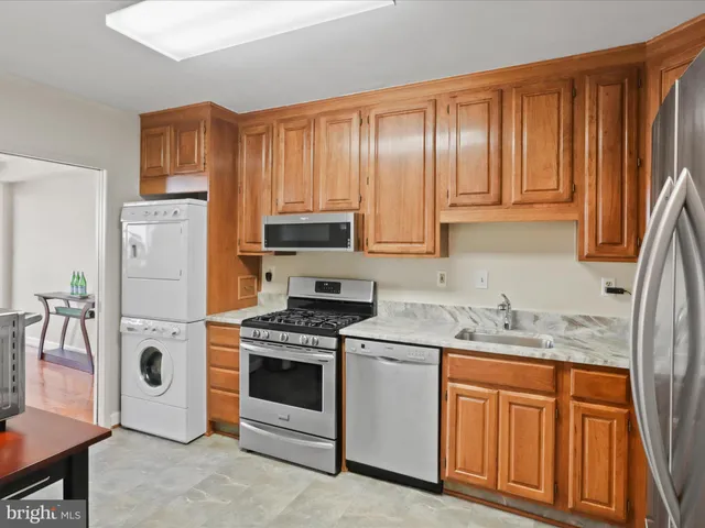 a kitchen with stainless steel appliances granite countertop a stove a sink dishwasher and a refrigerator with wooden cabinets