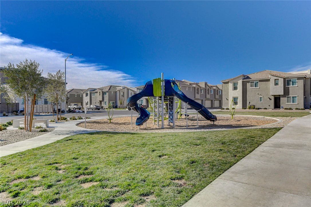 6924 Spicy Merlot Street North Las Vegas, NV 89086 - Photo 44 of 83 A community playground awaits, featuring a slide and climbing structure, set against a backdrop of modern townhomes.