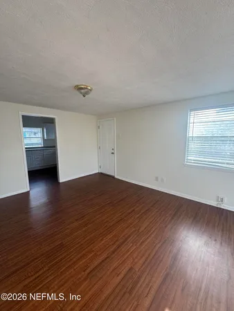 a view of empty room with wooden floor and fan