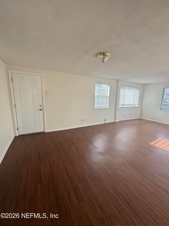 an empty room with wooden floor and windows