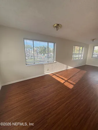 an empty room with wooden floor and windows
