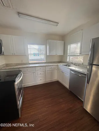 a kitchen with stainless steel appliances granite countertop a sink a stove a refrigerator with grey cabinets