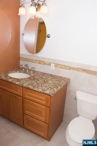 a bathroom with a granite countertop toilet sink and mirror