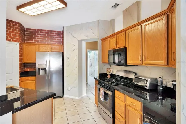 a kitchen with stainless steel appliances granite countertop a refrigerator a stove and a sink with wooden floor