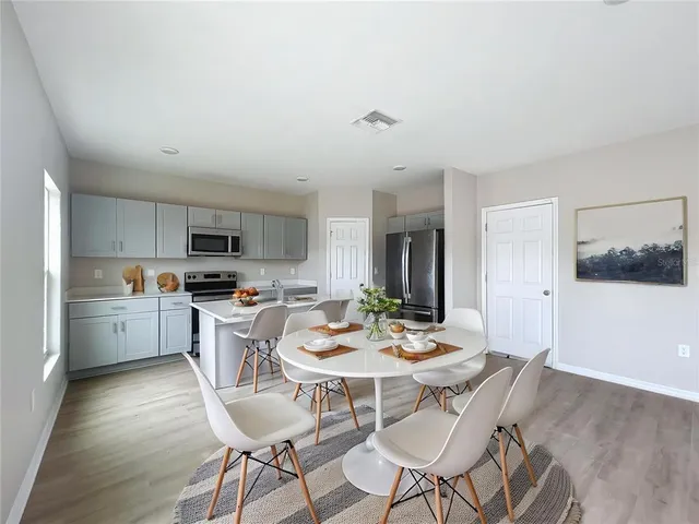 a kitchen with a dining table chairs and wooden floor