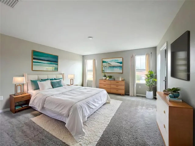 a bedroom with a large bed a flat tv screen and a couch