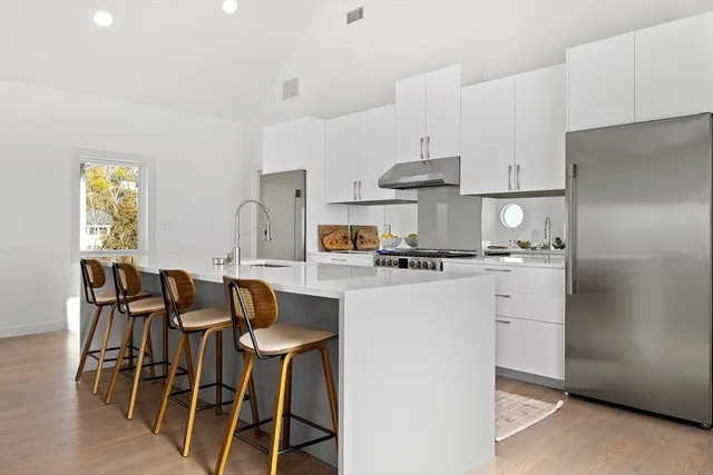 a kitchen with stainless steel appliances granite countertop a dining table chairs and a refrigerator
