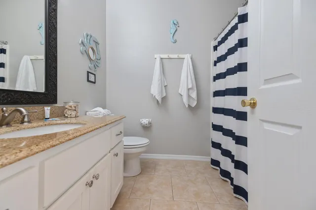 a bathroom with a granite countertop sink a toilet and a mirror