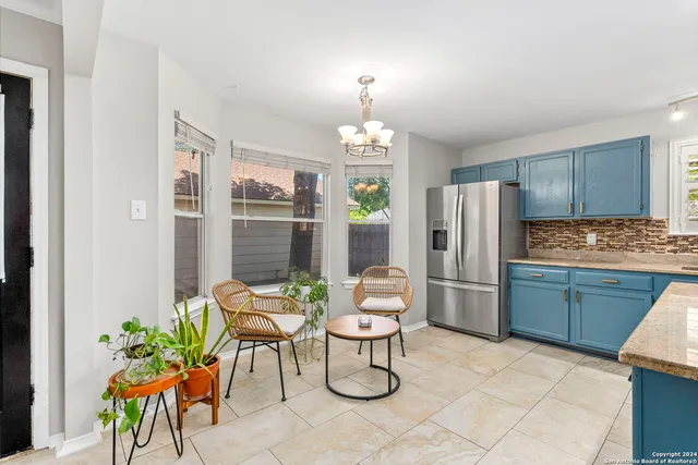 a kitchen with stainless steel appliances kitchen island granite countertop a refrigerator a stove a dining table and chairs with wooden floor