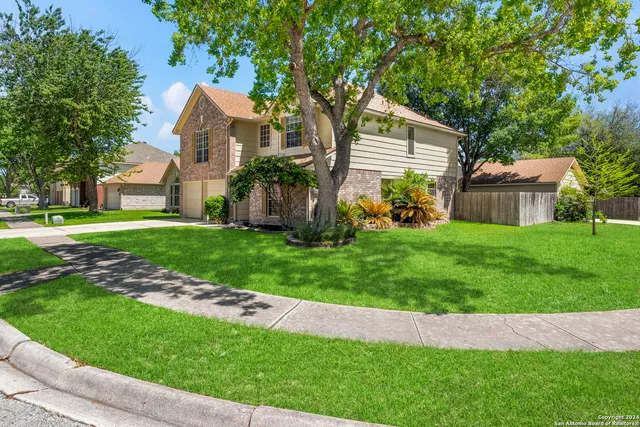 a front view of a house with a yard and tree