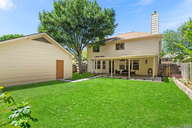 a backyard of a house with table and chairs and potted plants