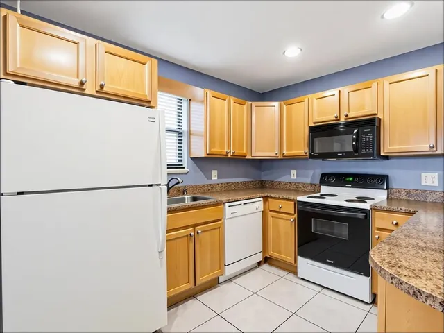 a kitchen with stainless steel appliances granite countertop a refrigerator a stove a sink a microwave and a refrigerator